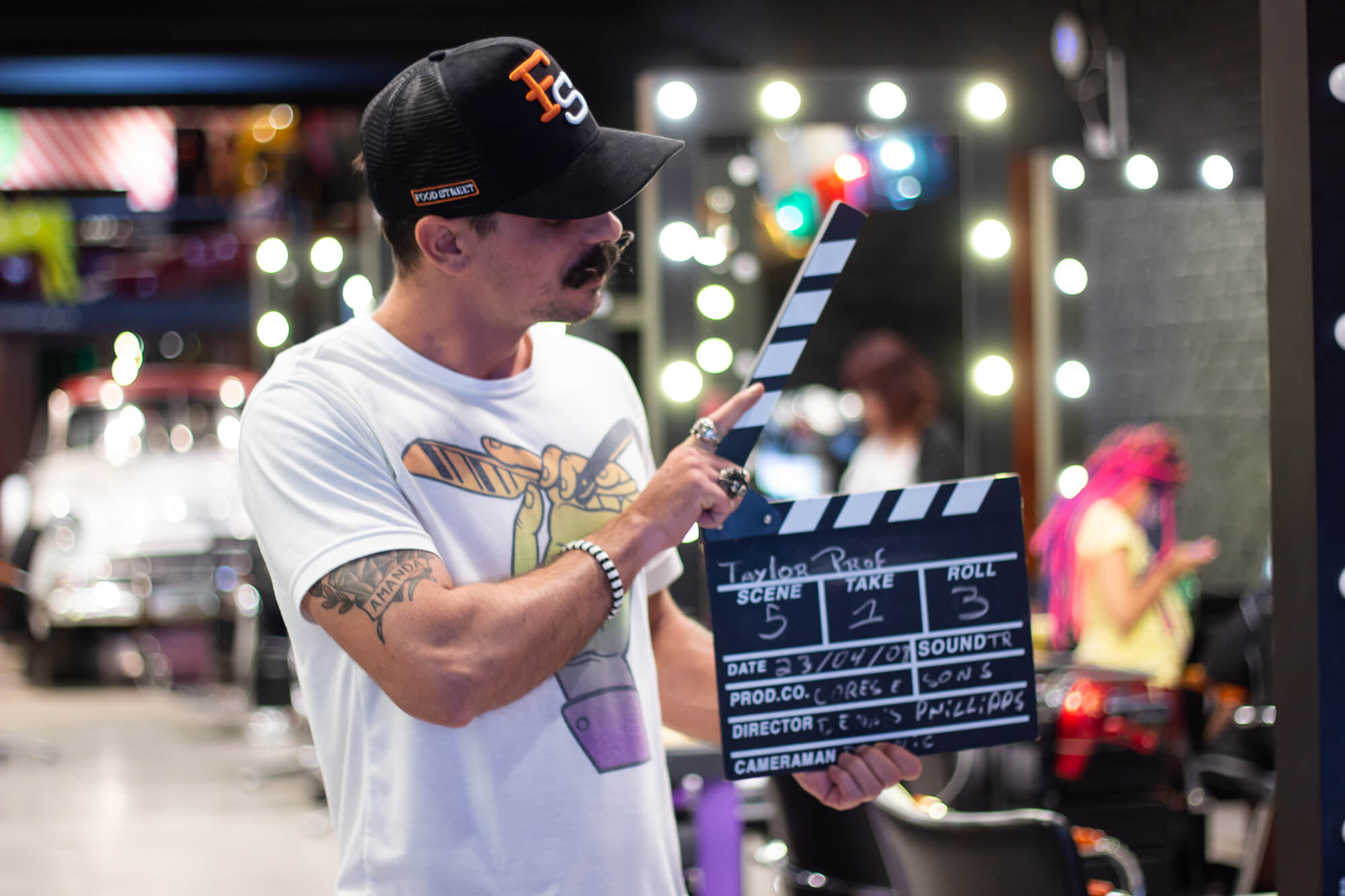 Set de filmagem com claquete em primeiro plano e equipe gravando ao fundo.